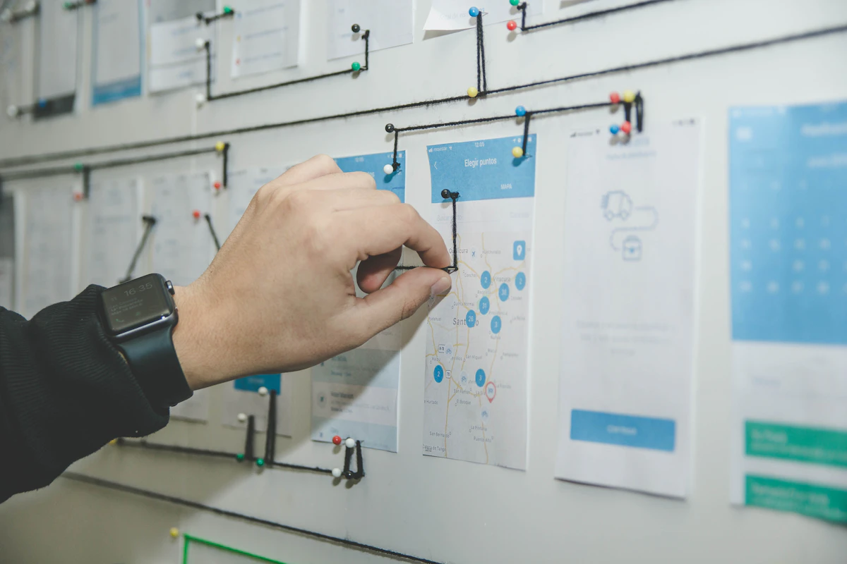 Designer arranging landing page wireframes and user flow screens on a wall