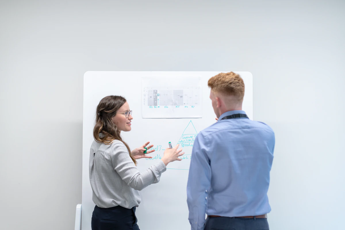 Two colleagues reviewing an automated SEO workflow at a whiteboard