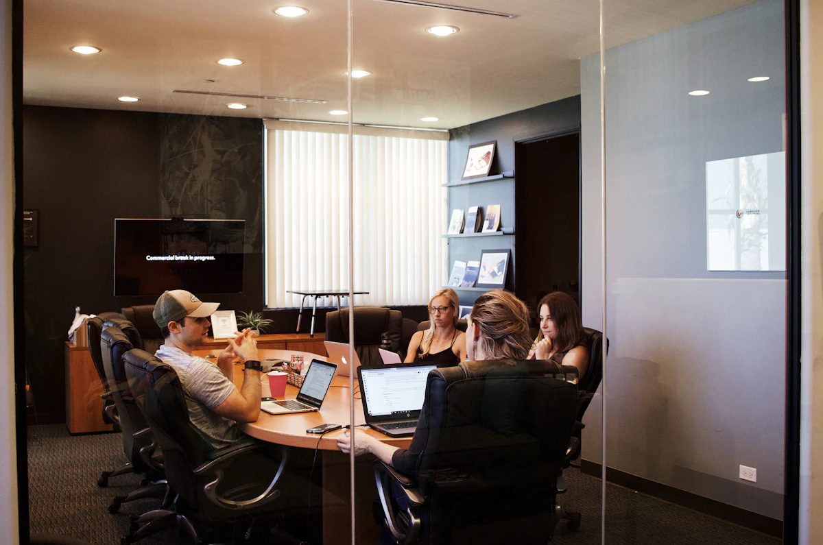Marketing team meeting around a conference table with laptops