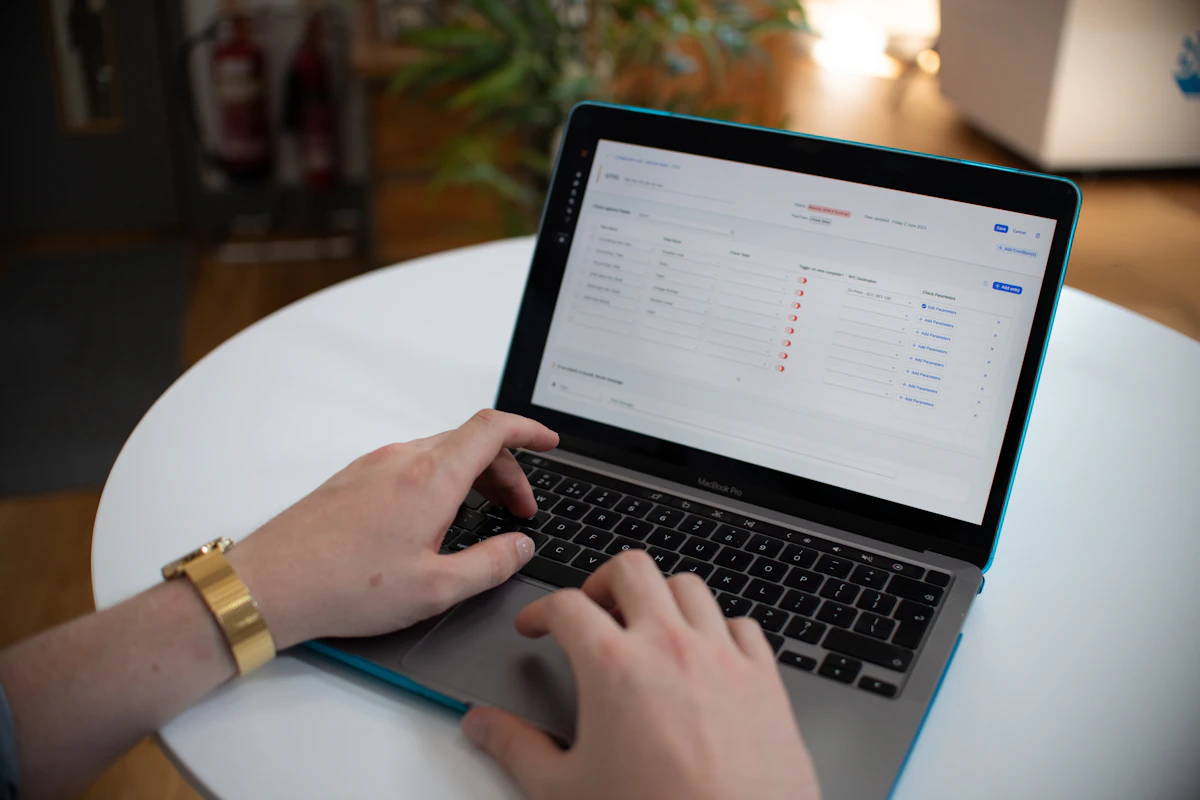 Hands typing on a laptop showing customer records in a spreadsheet